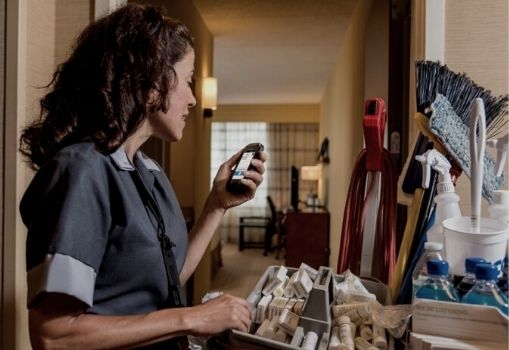 Housekeeping worker communicating with colleagues through push-to-talk capabilities on a mobile computer