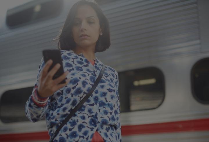 office worker looking at mobile phone in front of train