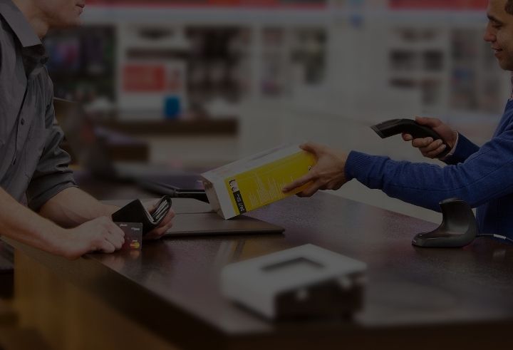 Retail worker scanning product while customer waits with payment card