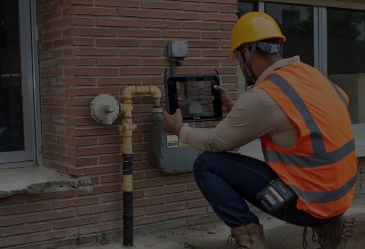 Utility field worker taking a photograph of a meter with a tablet device